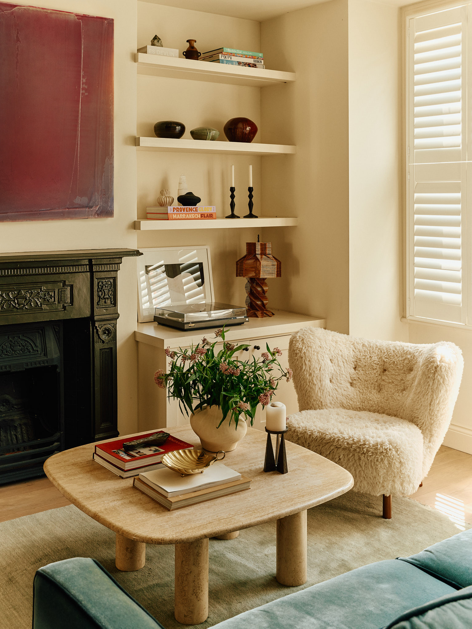 Fireplace, open shelves and a textured armchair beside a timber coffee table at School House
